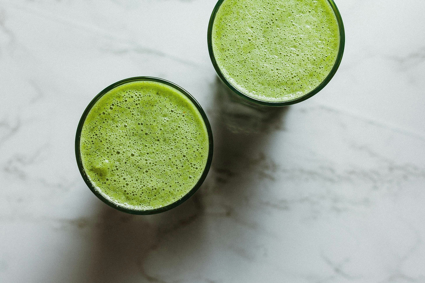 A green spirulina smoothie in a glass, showing how fresh spirulina blends into a drink